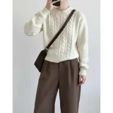 Sweater de punto color blanco marfil, con diseño de trenzas frontales, cuello redondo y mangas largas con puños elásticos acanalados.