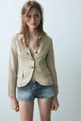 Blazer de cuello redondo con escote en pico, manga larga y cierre frontal con botones metálicos. Presenta falsos bolsillos con solapa en el delantero y un diseño estructurado.