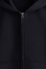 Campera con capucha de tejido efecto neopreno, con cierre frontal completo, hombros caídos y bolsillos delanteros abiertos. Presenta un corte holgado y diseño minimalista.