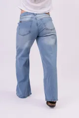 Pantalón wide leg de denim rígido, de tiro bajo en color celeste claro con sutiles desgastes, pernera ultra ancha y diseño de cinco bolsillos.