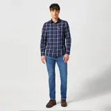 Pantalón de jean Wrangler corte slim, color azul medio, con bolsillos delanteros y traseros.