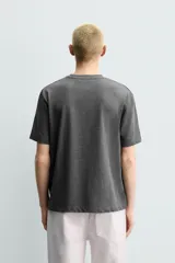 Camiseta regular fit de color beige, confeccionada en tejido de algodón compacto, con cuello redondo y manga corta.