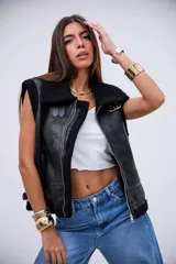 Chaleco de cuero sintético con acabado gamuzado, forrado en corderito negro. Presenta cierre frontal, cuello solapa, detalles de correas ajustables en los laterales y ribetes de corderito en los bordes.