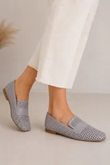 Mocasines chatos de cuero vacuno en color celeste, con diseño calado en toda la superficie y detalle de tira lisa en el empeine. Poseen suela plana y taco bajo de goma.