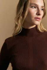 Polera de tejido acanalado con cuello alto, corte ajustado al cuerpo y mangas tres cuartos con terminaciones onduladas en los puños.