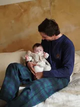Pijama de dos piezas compuesto por una camiseta de manga larga azul marino con logo bordado en el pecho y un pantalón largo de corte recto con estampado de cuadros en tonos azul y verde.