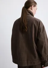 Chaqueta de algodón estilo tejano vaquero, color marrón, de diseño oversize con cuello alto, manga larga, bolsillos delanteros de parche y solapa, y cierre frontal con botones.