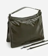 Cartera tipo hobo de gran tamaño confeccionada en poliuretano color negro, con acabado liso y brillante. Presenta un diseño de media luna con cierre superior de cremallera, correa de mano fija y asa larga desmontable. Incluye un detalle de cremallera lateral que permite expandir su capacidad interna.