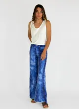 Pantalón de jean con estampado batik en tonos azules y blancos, corte acampanado y ruedo desflecado.