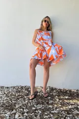 Vestido corto sin mangas con estampado abstracto en tonos naranja y celeste.