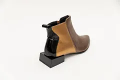 Botín corto de cuero negro con detalle de cuero dorado en el talón y textura de cocodrilo en el lateral. Tiene cierre lateral y taco cuadrado.