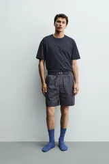 Set de pijama compuesto por una remera lisa de manga corta con cuello redondo y una bermuda a cuadros con bolsillos laterales y cintura elástica.
