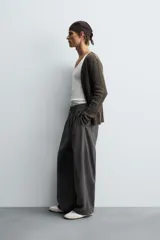 Pantalón de corte relajado, color gris oscuro, con cintura elástica ajustable mediante cordón y pliegues frontales. Presenta bolsillos laterales y bolsillos traseros de parche con pespuntes contrastantes.