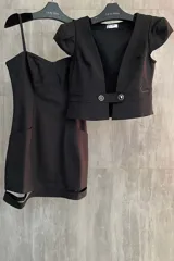 Conjunto de dos piezas color negro compuesto por un vestido corto entallado con aberturas laterales en el ruedo y un bolero de manga corta con cierre frontal de botones.