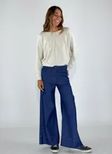 Chaqueta marrón con cuello camisero, cierre frontal con botones, bolsillos de parche y ruedo desflecado.