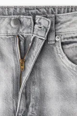 Jeans de cinco bolsillos en denim de algodón rígido, color gris claro lavado. Presenta un corte de cintura ultra alta, pierna amplia y recta desde la cadera hasta el bajo, con un estilo levemente largo.