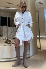 Vestido camisero de algodón blanco, de silueta amplia y largo mini. Presenta cuello clásico, cierre frontal con botones de madera y lazo regulable en la cintura. Posee bolsillos amplios.