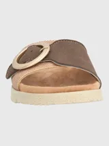 Sandalia tipo slide con tira ancha de tejido texturizado en tono beige y detalle de hebilla circular decorativa en color marrón. Cuenta con plantilla anatómica y suela de poliuretano dentada en color crema.