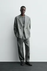 Blazer de corte relajado confeccionada en lino, con diseño de botonadura cruzada, cuello con solapas de muesca, manga larga y bolsillos ocultos en las costuras laterales.