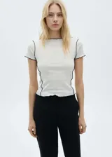 Remera blanca de corte slim con cuello redondo y mangas cortas. Presenta terminaciones con puntada overlock en color negro.