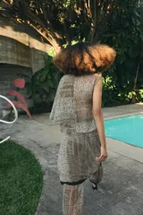 Falda pantalón de tiro bajo con estampado de puntos negros sobre fondo beige. Presenta un diseño de superposición con cierre lateral mediante lazadas y cremallera oculta, finalizando en bordes con detalle de franja negra.