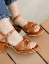 Sandalias de cuero color dorado, con plataforma y taco cuadrado. Presentan tiras cruzadas en el empeine y pulsera al tobillo con hebilla.