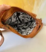 Bandolera Orlena de la línea Ottenta, confeccionada artesanalmente con cueros uruguayos seleccionados con distintas texturas. Presenta un diseño combinado en negro, marrón con textura símil cocodrilo y detalles en tono dorado, con correa ajustable para usar al hombro o cruzada y herrajes de metal.