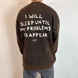 Buzo marrón con efecto gastado, corte oversize y estampa en la espalda con la frase "I will sleep until my problems disappear".