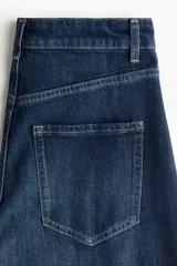Jean wide leg de tiro alto en denim de algodón azul, con costuras frontales verticales y bolsillos simulados con solapa y botones en la parte delantera.