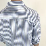 Camisa de vestir a rayas verticales azules y blancas, de corte clásico, con cuello italiano y mangas largas con puños abotonados. Presenta logo bordado en el pecho. Marca Duxon.