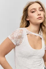 Top de encaje blanco con diseño ajustado al cuerpo, mangas cortas y detalle de cut-out en el escote.