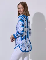 Buzo tejido en hilado fino, con cuello redondo y mangas 3/4. Presenta un estampado floral en tonos azules sobre un fondo a rayas verticales en diferentes tonos de azul.