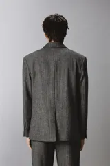 Blazer de corte relajado confeccionado en tejido con lana, con diseño de espiga. Presenta cuello con solapas de muesca, cierre frontal de botonadura cruzada, bolsillos de vivo en el pecho y bolsillos de solapa en la cadera.