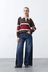 Sweater de tejido de punto con diseño a rayas horizontales en tonos marrón, rojo y crema. Presenta cuello tipo polo con cierre frontal de botones y mangas largas con puños ajustados.