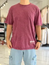 Remera oversize de color bordó con efecto gastado acid wash, mangas cortas y estampa en la espalda con texto y logo.