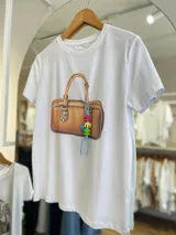 Remera blanca de algodón con estampa de una cartera marrón con llavero de letras de colores.