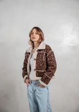Campera de gamuza con estampado animal print de leopardo, forrada en corderito sintético color crema. Presenta cierre frontal con botones tipo toggle, cuello solapa y detalles de costuras visibles.