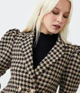 Blazer corto de tweed con estampado de cuadros pied-de-poule, cuello solapa, mangas abullonadas y cierre con doble botón.