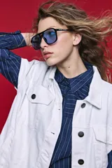 Chaleco de jean color blanco, de corte oversized, con cuello camisero, bolsillos delanteros con solapa y cierre frontal por botones metálicos.