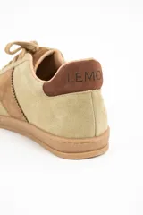 Zapatilla de gamuza en tono verde pistacho con detalles en cuero marrón, cordones al tono con cuentas decorativas y suela de goma color caramelo.