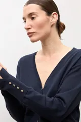 Cardigan negro con escote en V, manga larga y cierre frontal con botones pequeños. Presenta puños acanalados con detalle de botones decorativos.