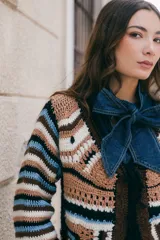 Saco tejido en crochet con diseño de rayas horizontales en mangas y espalda. Presenta un cierre frontal con lazos de crochet en el escote en V y detalle de flecos en el ruedo.