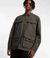 Campera masculina color verde oliva, estilo parka, confeccionada en sarga de algodón. Cuenta con cuello con solapa, cierre con botones, manga larga y múltiples bolsillos táticos delanteros.