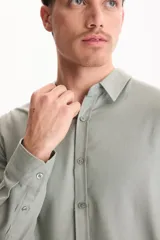 Camisa de lino de manga larga, color beige, con cuello clásico y cierre frontal de botones.