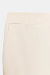 Pantalón de corte recto y tiro bajo, color marrón oscuro. Presenta trabillas en la cintura, bolsillos laterales, falsos bolsillos traseros de vivo y raya planchada en el delantero. Cierre frontal con cremallera, botón interior y ganchos metálicos.