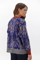 Sweater de punto con estampado animal print en tonos marrones, negros y blancos. Tiene cuello redondo, puños y bajo acanalados en color marrón y gris.