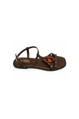 Sandalias planas Daniel Cassin de color marrón, con tiras finas y una piedra decorativa ovalada en el empeine. Cuentan con tira ajustable en el talón y hebilla metálica dorada.