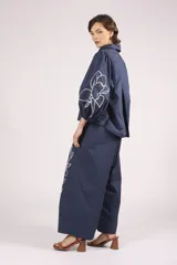 Pantalon de corte ancho y tiro alto, color azul marino, con bordados florales en color crema en la parte inferior de las piernas.