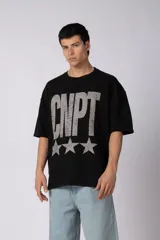 Remeron de corte oversize color negro, con estampa frontal en color gris desgastado que incluye el texto 'CNPT' y tres estrellas. Presenta cuello redondo y mangas cortas amplias.