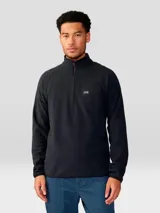 Buzo de polar con cierre frontal de 1/4, cuello alto y mangas raglán. Presenta un diseño minimalista en color negro con el logo de la marca bordado en el pecho.